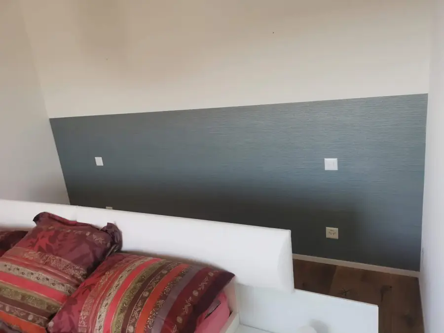 Schlafzimmer mit grau gestrichener Akzentwand hinter dem Bett