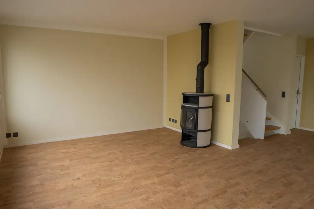 Renovierter Wohnraum mit gelb gestrichenen Wänden und Schwedenofen – Kreativ Maler